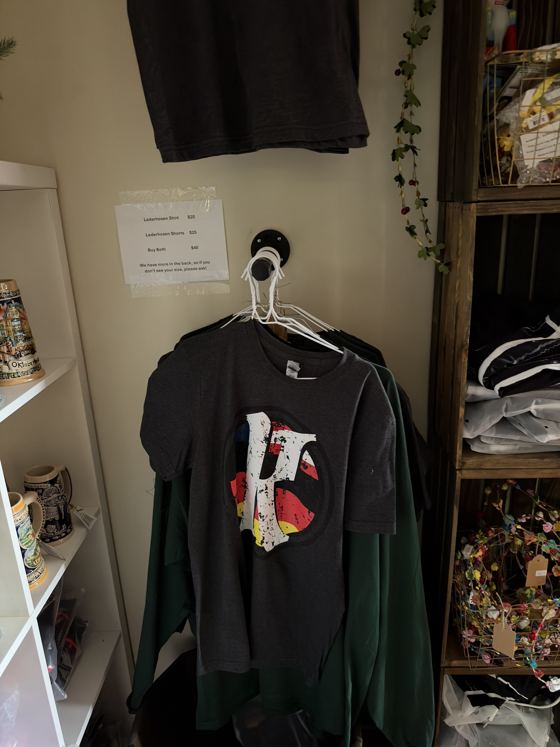 Krush Brau Park gift shop apparel wall with KB logo tee, steins and lederhosen price sign